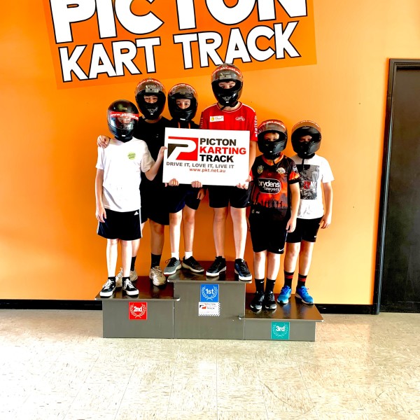 Racing track winners standing on a podium holding their certificate