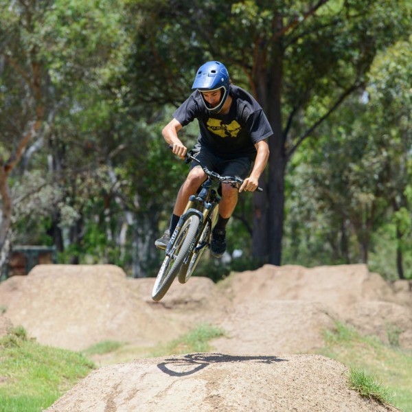 BMX rider doing a stunt and flyer over dirt hill