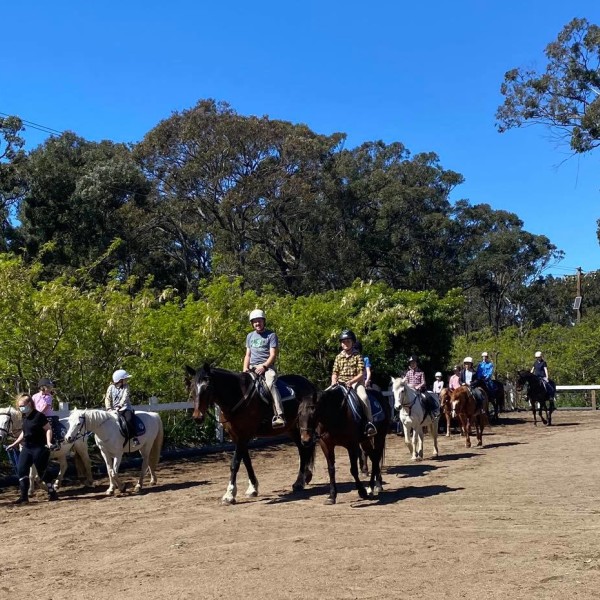 Group of pony riders walking around an enclosure