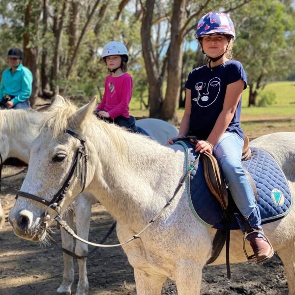 White horses with smiling riders sitting in their saddles at Endeavour Park Equestrian Centre