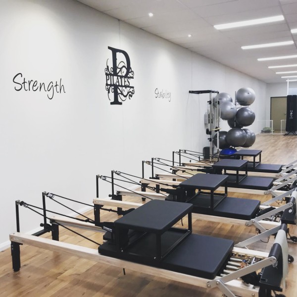 Reformer Pilates classroom with pilates equipment set up and 'strength' written on the wall