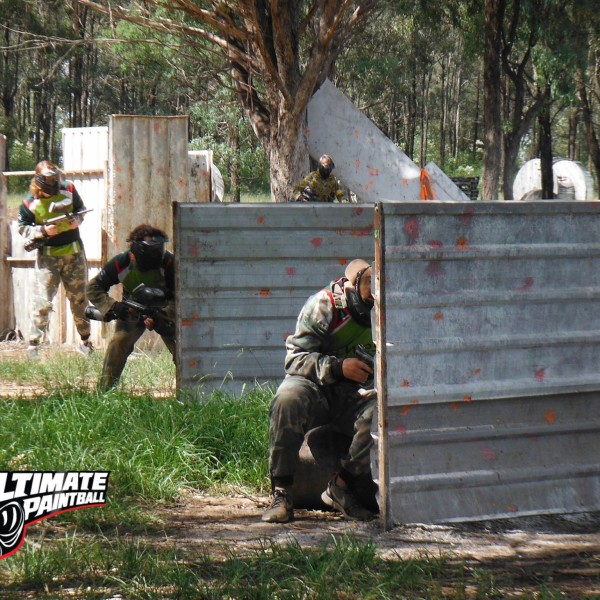 Guys dressed in camo hiding behind old shed panels at Ultimate Paintball Battlefield