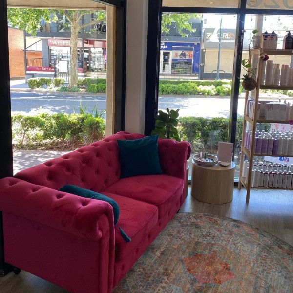 Red waiting couch and product display at El J & Co Hair Salon