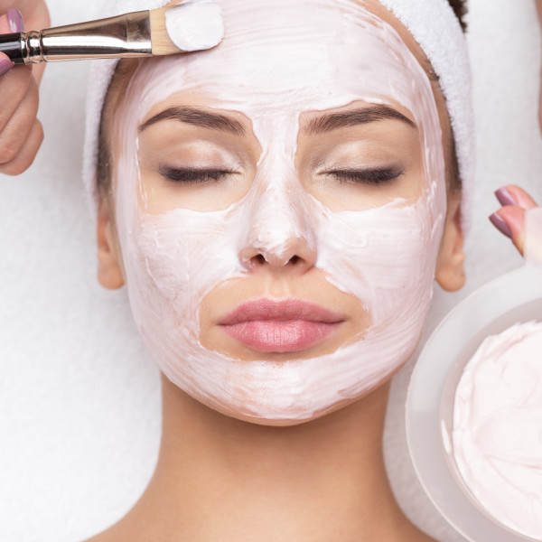 Lady with pink facemask being applied by beauty therapist