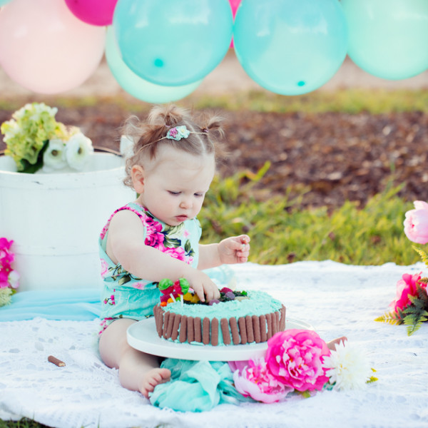 Little girl sitting with cake and balloons