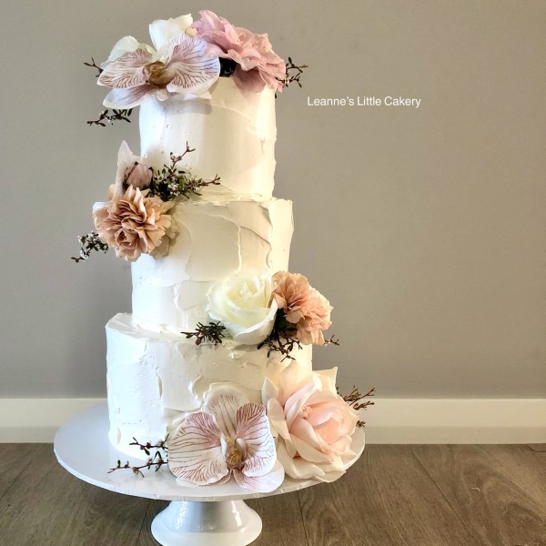 Three Tier iced wedding cake with variety of pink flowers