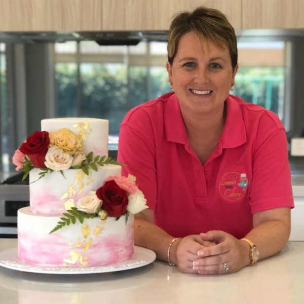 Leanne beside a wedding cake with flowers